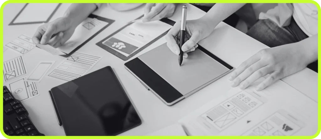 Hands sketching wireframes and working on digital devices during a web design strategy session